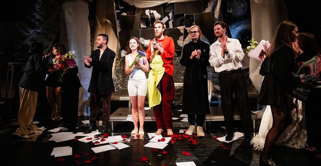 Actors holding flowers are standing on the theater stage 